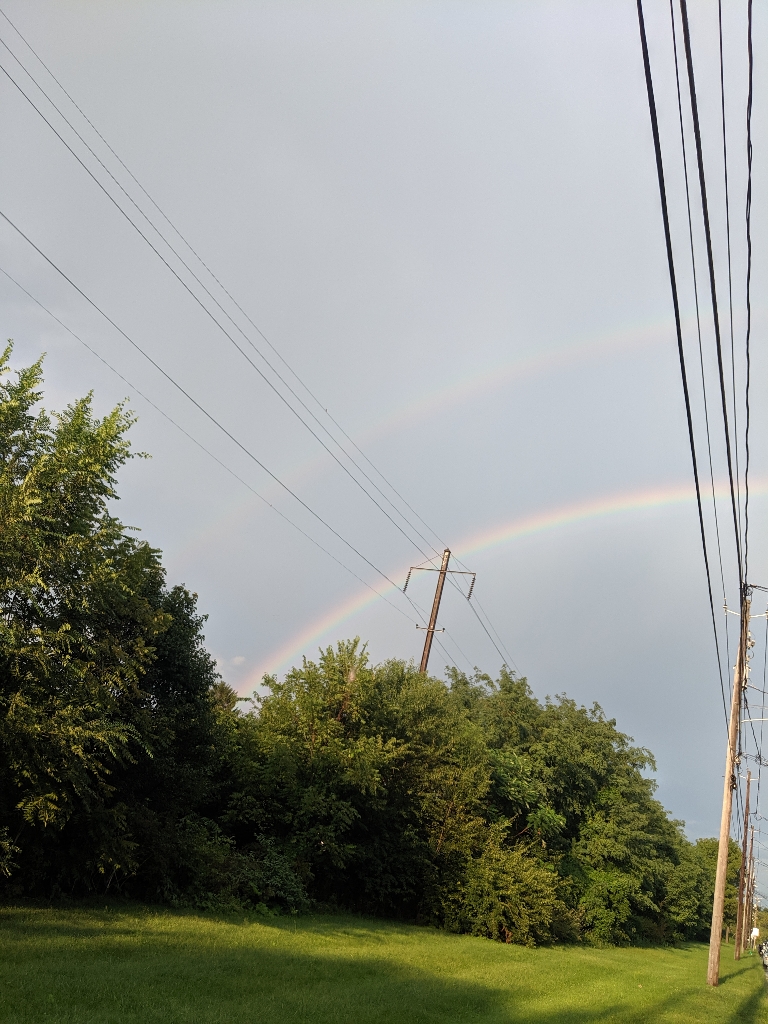 This is a photo of a double rainbow over a small open area.