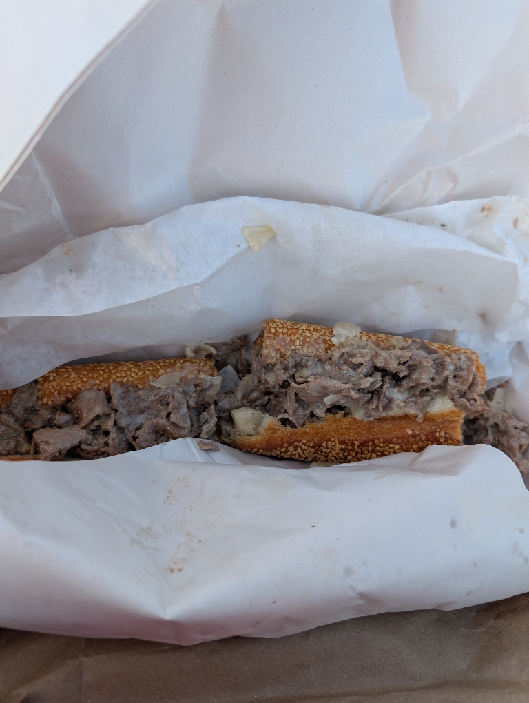 This picture shows a cheese steak loaded with meat and cheese.