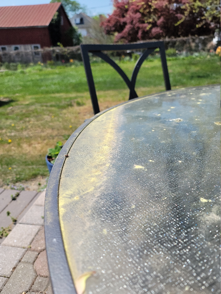 This picture green pollen pushed into a tiny drift on a green glass patio table.