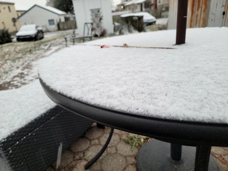 In this pictuere there is a green patio table with a coating of fresh snowfall.