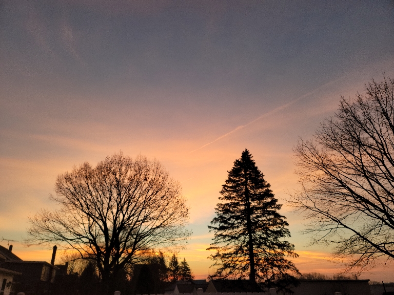 This picture is of a sunrise. The colors in the sky range from purplish to bright pink and orange from the sun hitting the clouds.