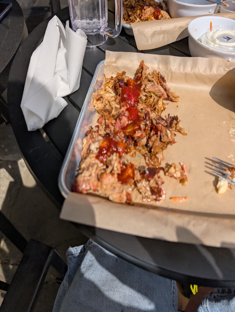 This is a picture of some pulled pork on a tray outside in the sun.