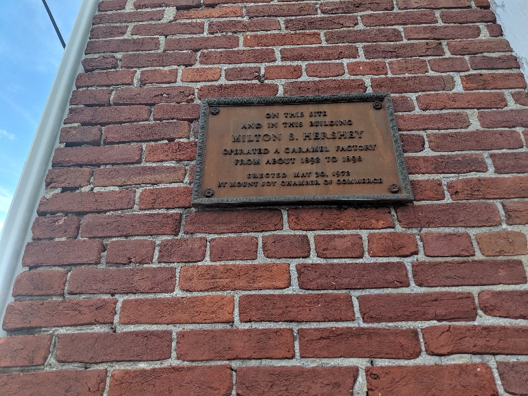 This picture of a plaque on a brick building wall. The plaque says 