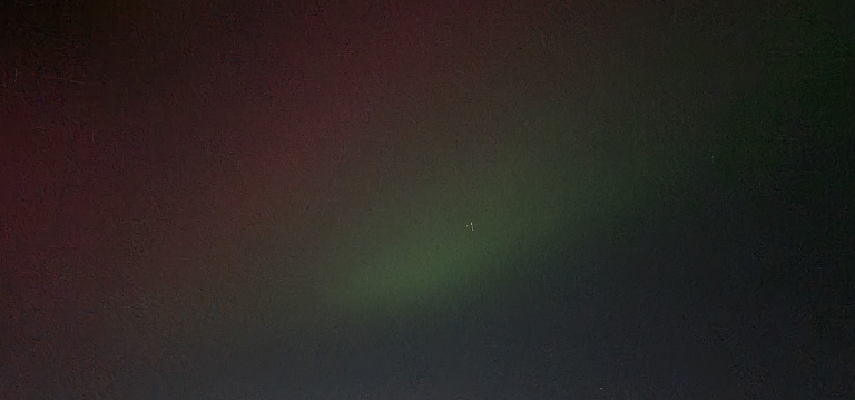 In this picture there are multi colored northern lights. It's mostly red with some green or even bluish glows to the right side.