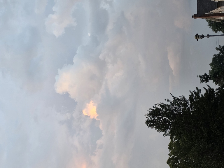 This picture shows low grey clouds with some cumulus clouds being brightly illuminated by the sun visible through breaks in the lower clouds.