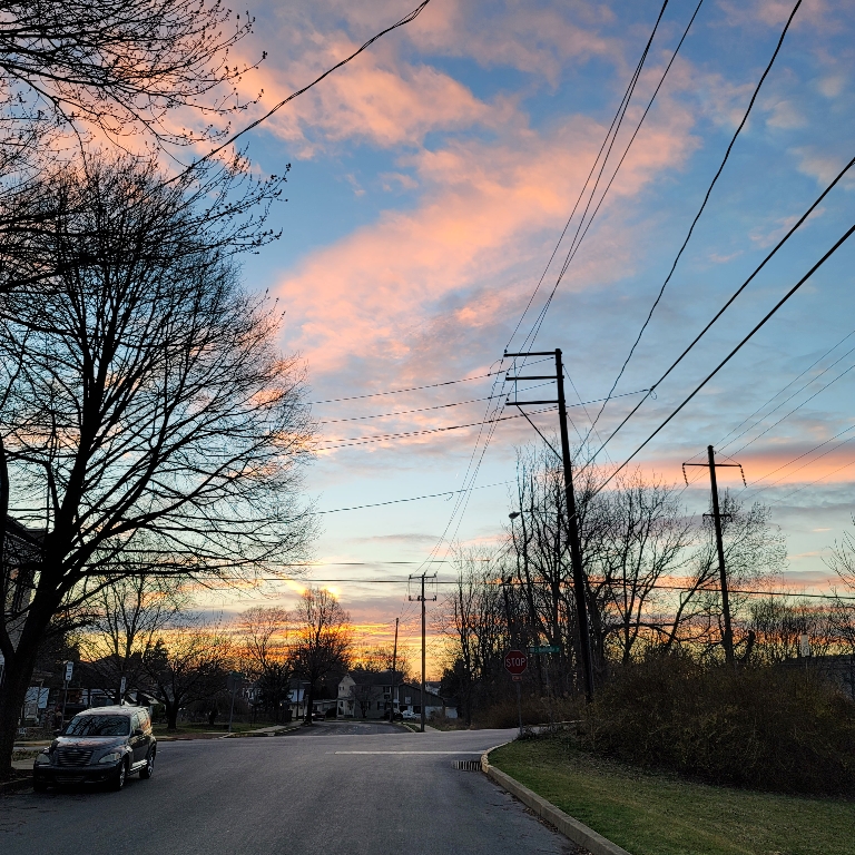 This picture is of a sunset. The sky is filled with orange clouds lower on the horizon with some pink clouds above it.