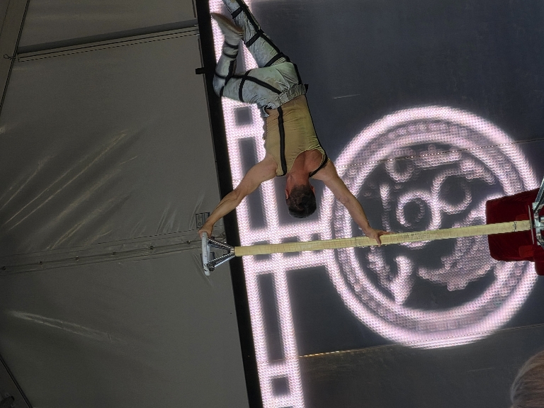 This photo shows a man performing on a pole holding his body horizontally.