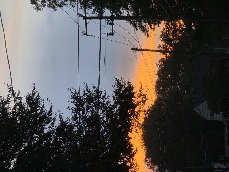 Here is a photo of an orange sunset over a street as the clouds were moving out from a thunderstorm.