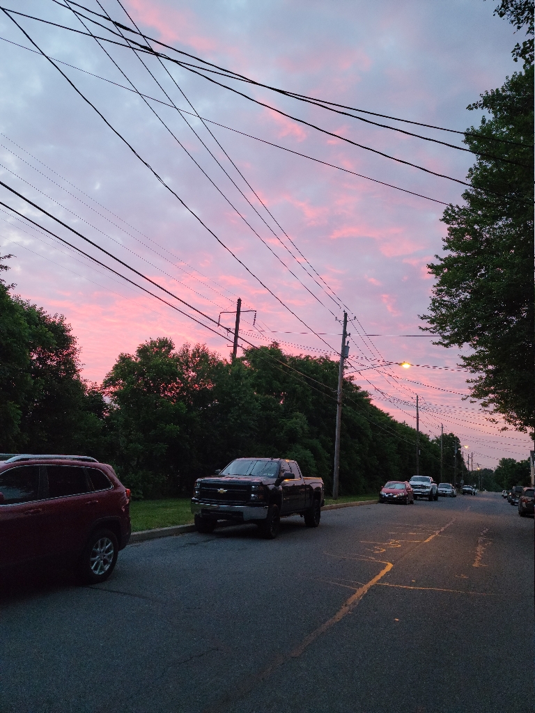 This picture is of a sunrise. The colors in the sky range from purplish to bright pink and orange from the sun filtiner through the high clouds.