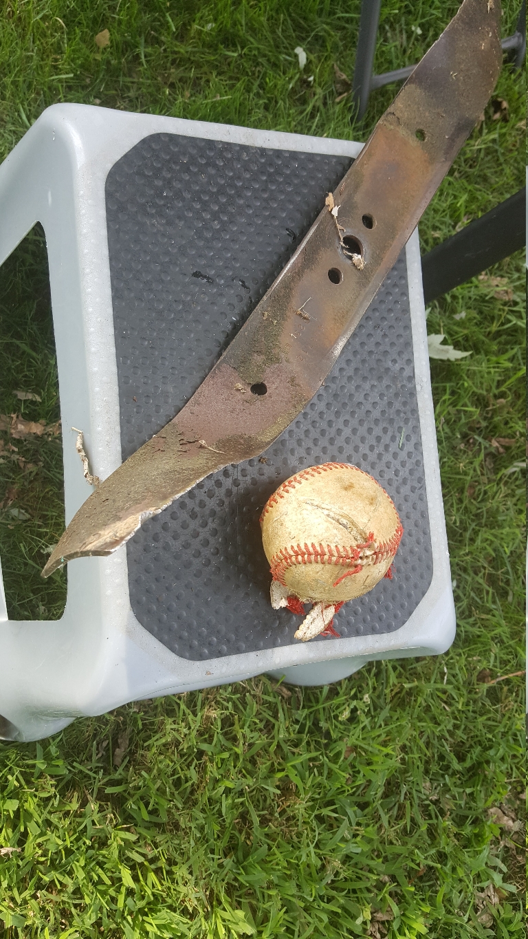 This is a picture a bent lawnmower blade on a step stool next to the ball that bent it when I ran it over.