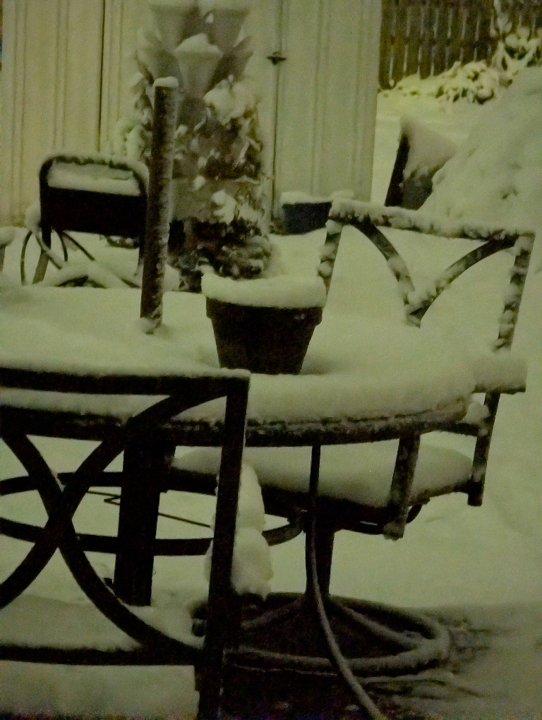 This is a picture of snow on a table and ont he patio.