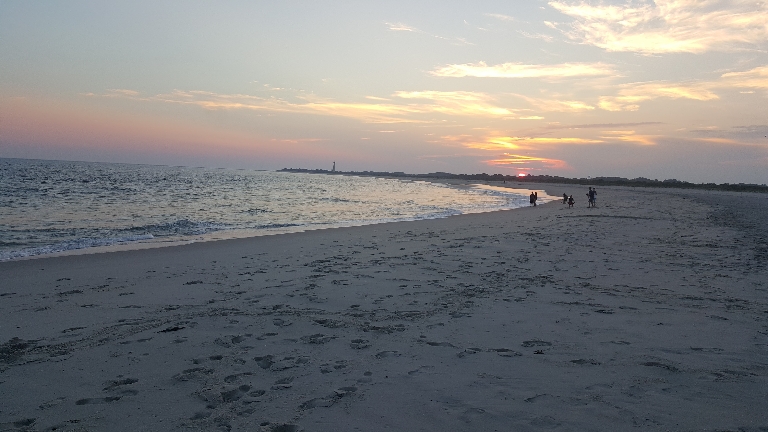 This is a picture of a sunset over the Cape May Point peninsula with the lighthouse in the same picture