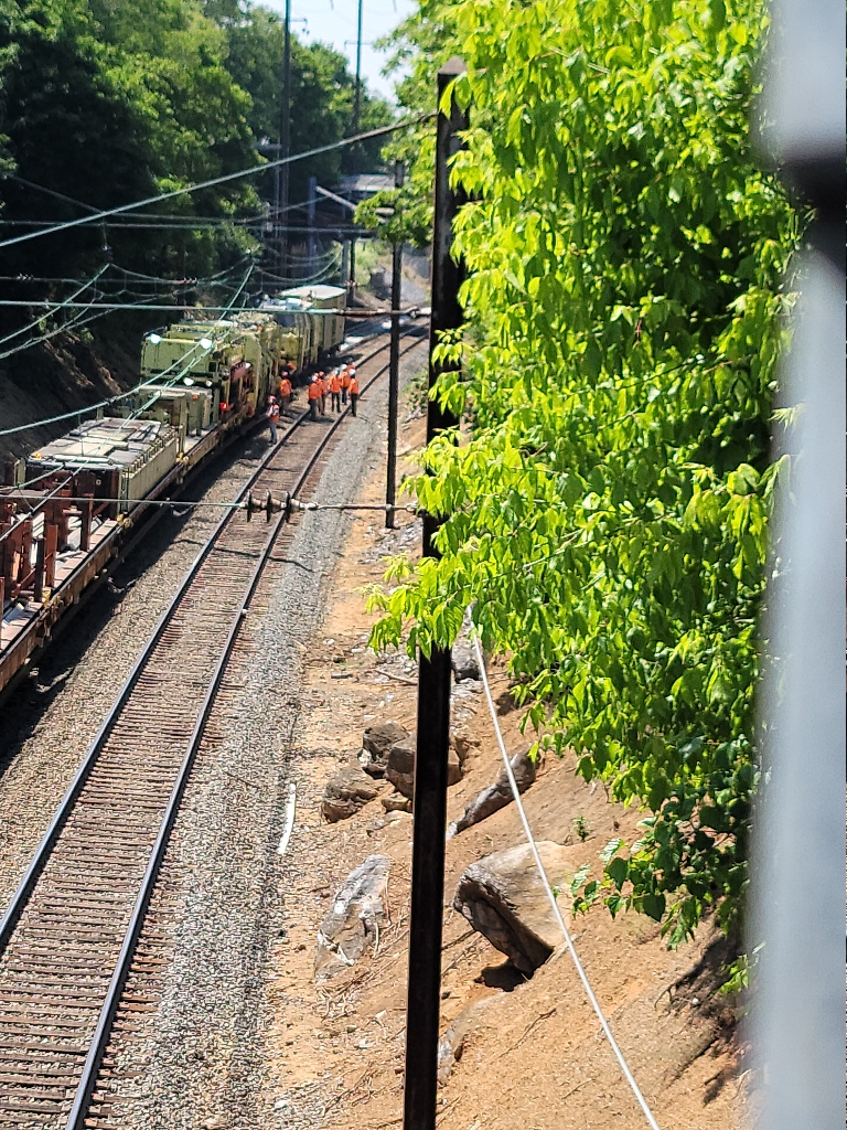 This picture shows a large machine on the railroad tracks. It's got a bunch of ties on it and other things.